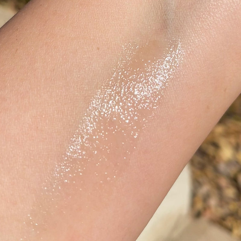 A close-up of bare skin showing a swatch of Pom Pom Dog Balm. Swatch is clear and shiny.